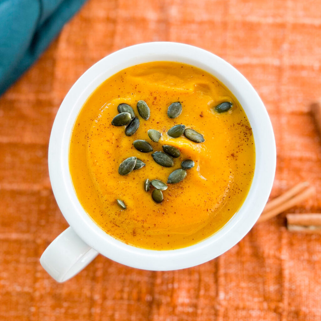 Butternut squash soup in white bowl with pepitas