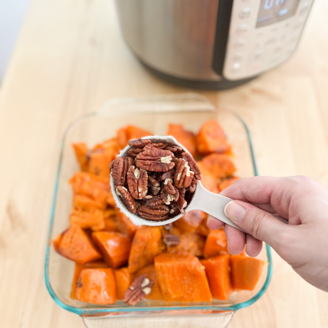Candied yams with pecans in measuring cup.