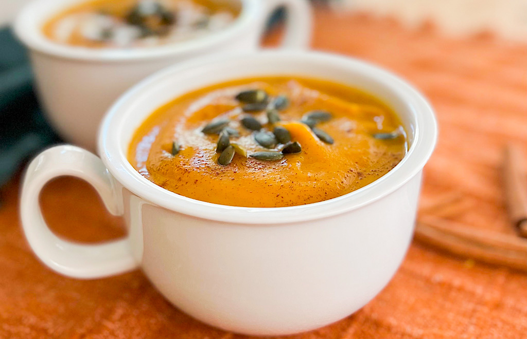 Butternut squash soup with pepitas in white bowls