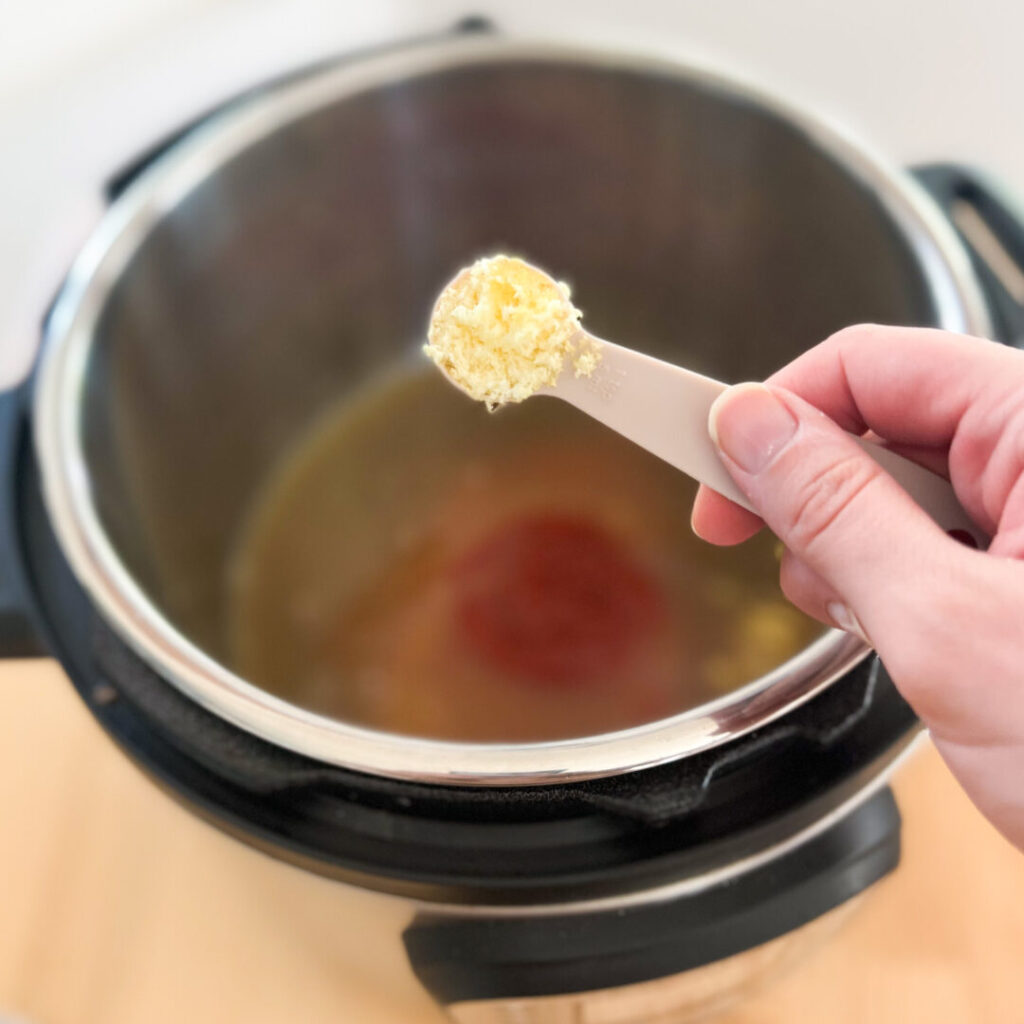 Ginger in a measuring spoon over an Instant Pot.