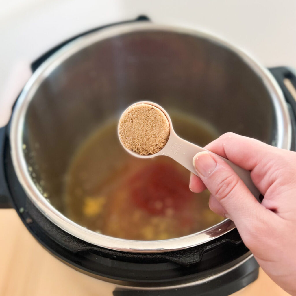 Brown sugar in a measuring spoon over an Instant Pot.