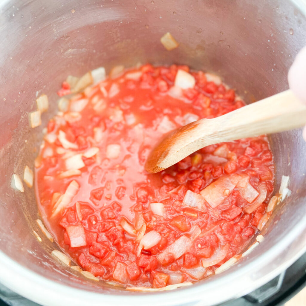 Stirring onions and tomato in an Instant Pot.