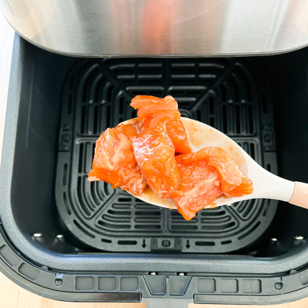 Adding raw salmon to air fryer.
