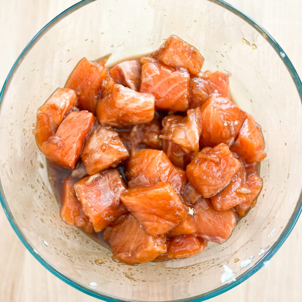Salmon in a bowl mixed with ingredients.