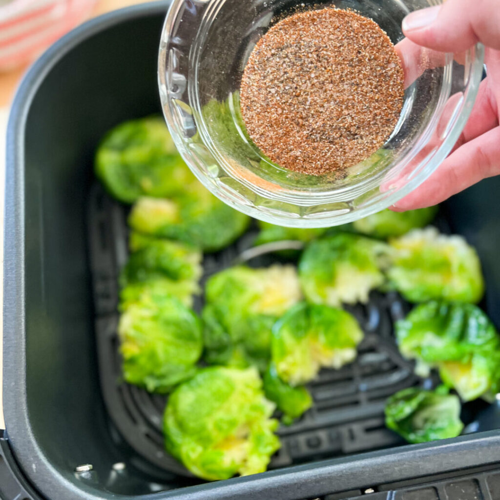 Sprinkling seasoning on the brussels sprouts.