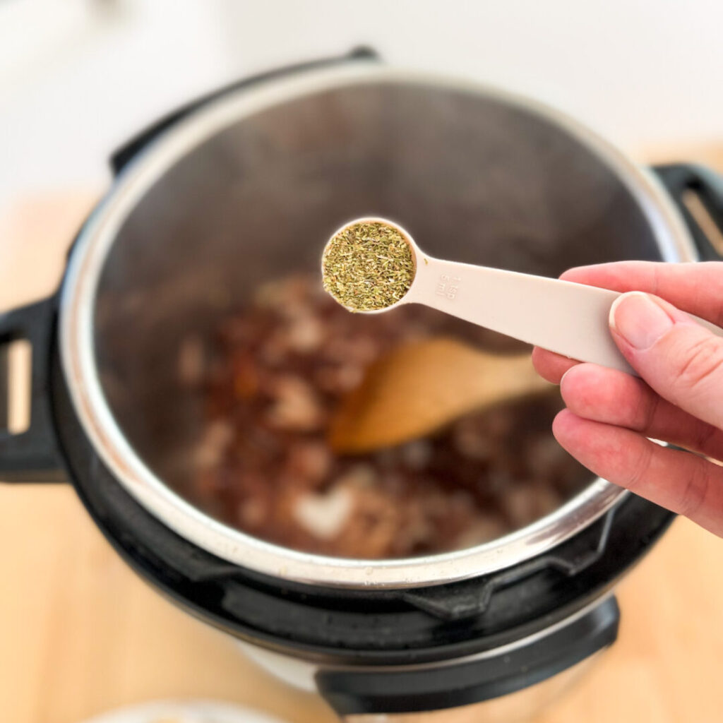 Adding Italian seasoning to the Instant Pot.